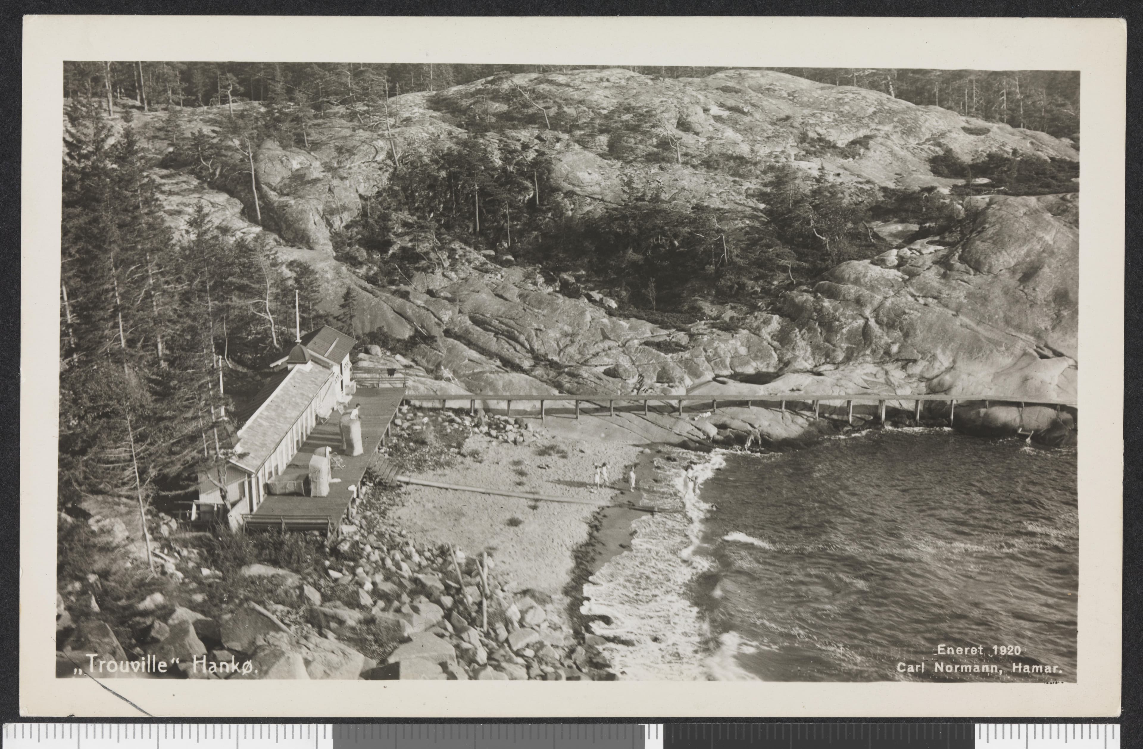 Historisk svart-hvitt postkort fra Hankø med badehus langs en steinete strand.