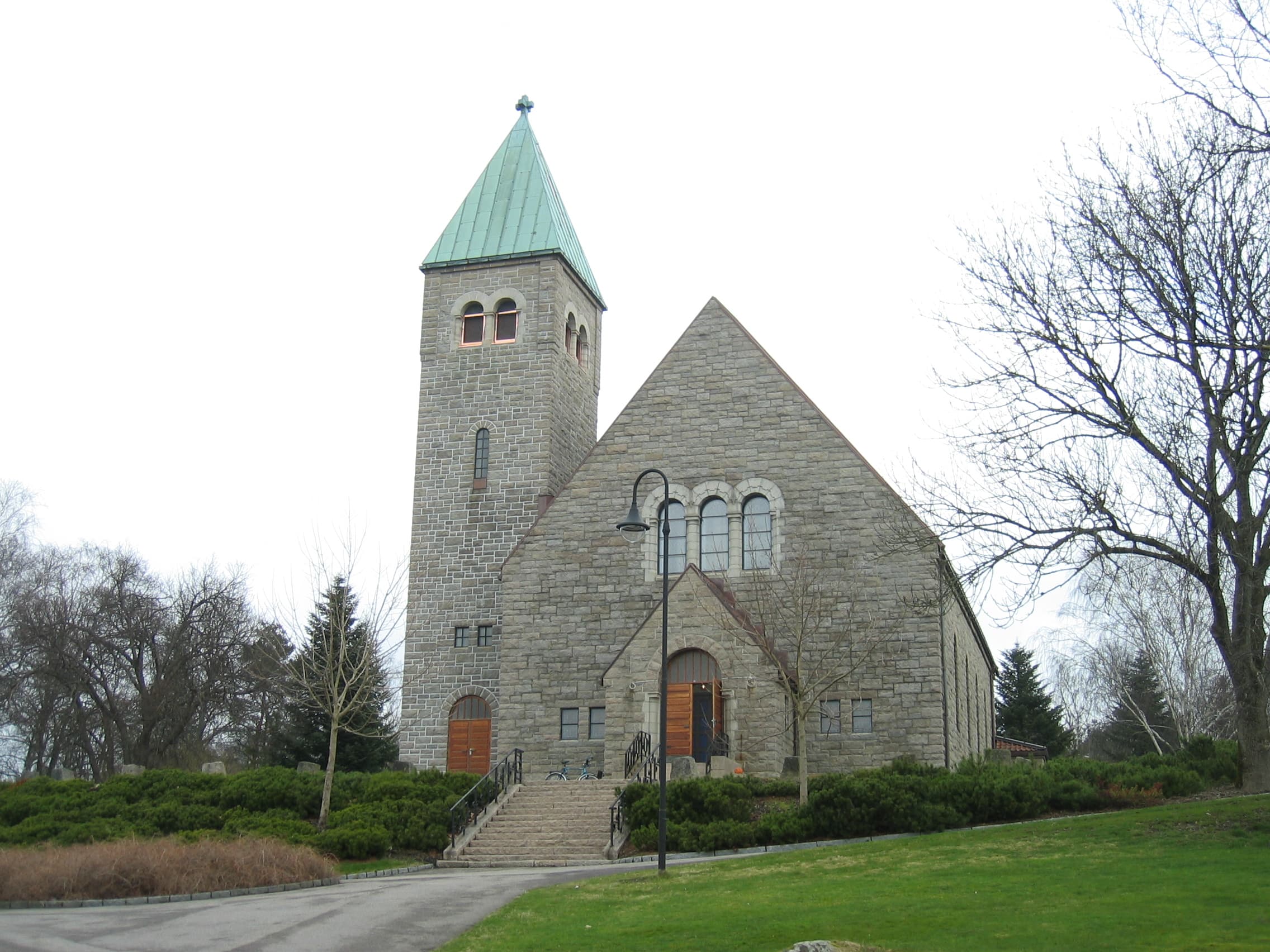 Gressvik kirke, en grå steinkirke med tårn og grønt kobberspir.